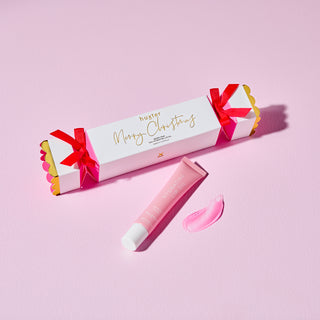 Pink lip balm with decorative packaging on a pink background