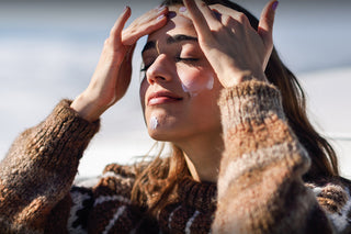 Winter skin | A lady wearing a jumper with her fingers to her forehead