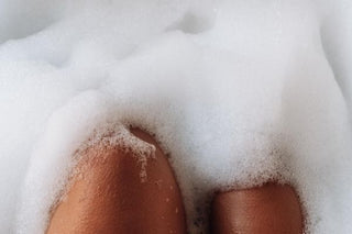 A lady submerged in a bubble bath showing just her knees